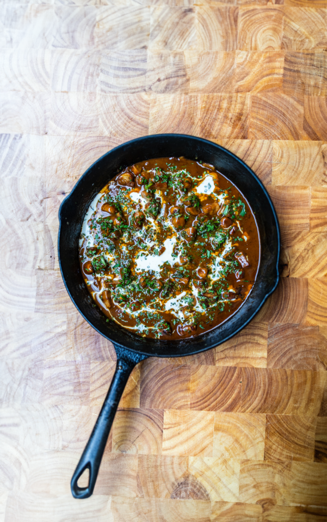 Overhead shot of Sauce Diane in a cast iron pan on a wooden background.