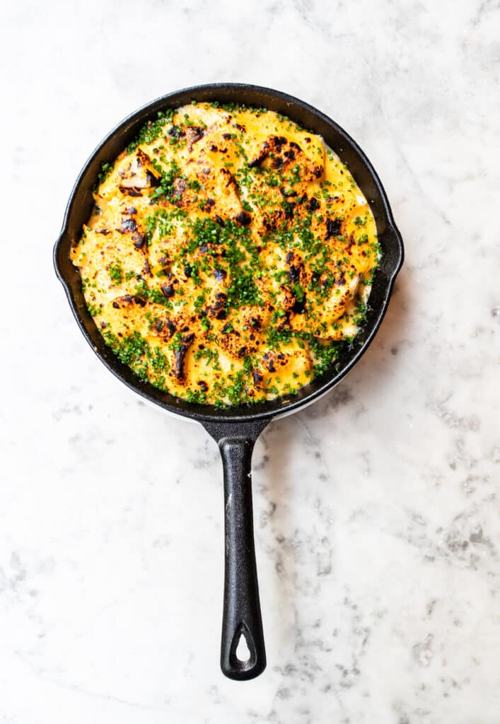 Overhead shot of an Arnold Bennet Omelette in a cast iron pan on a white marble table top