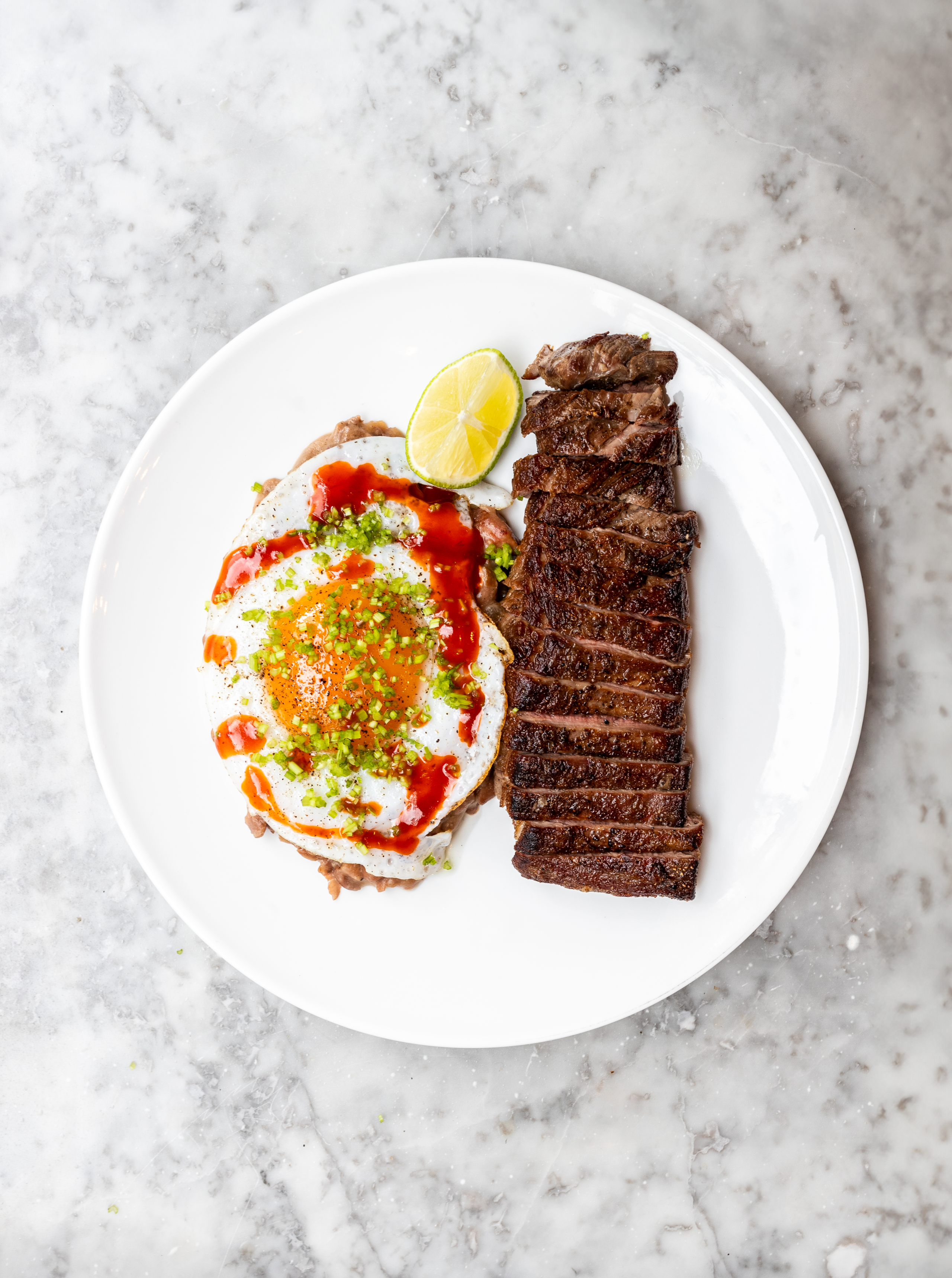 Overhead shot of refried beans with fried egg and bavette steak